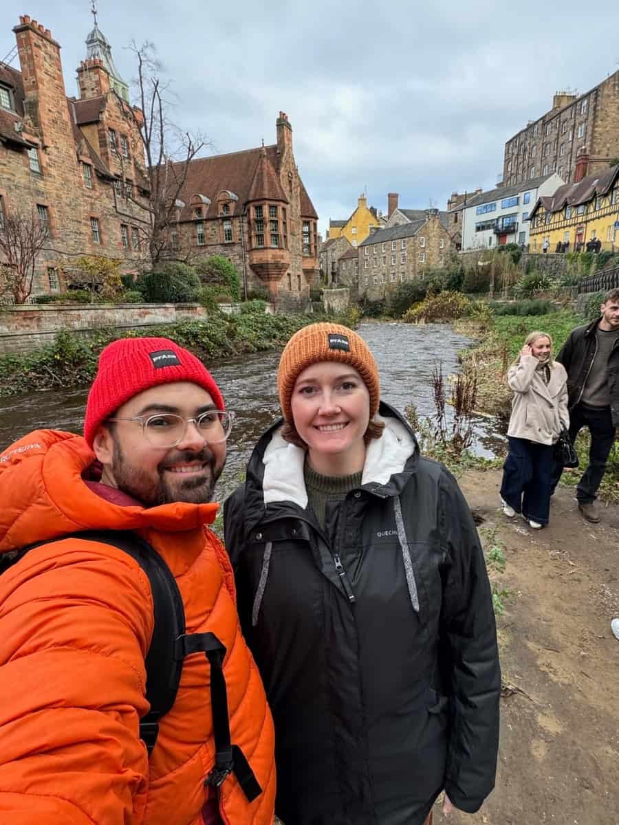 Katie and Joe standing together in Dean Village, a historic neighborhood in Edinburgh, Scotland.