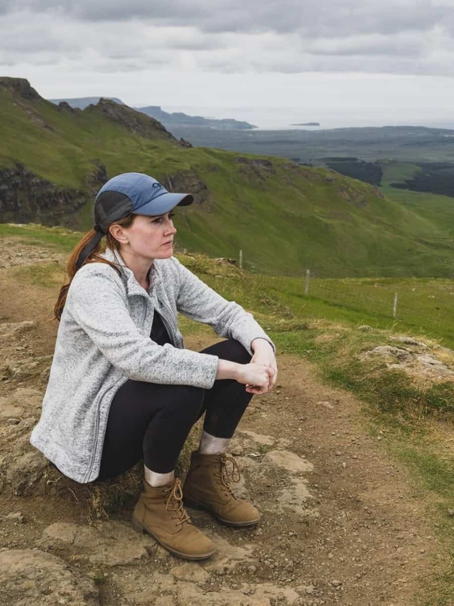 Katie sitting on a hillside overlooking the Old Man of Storr on the Isle of Skye in Scotland.