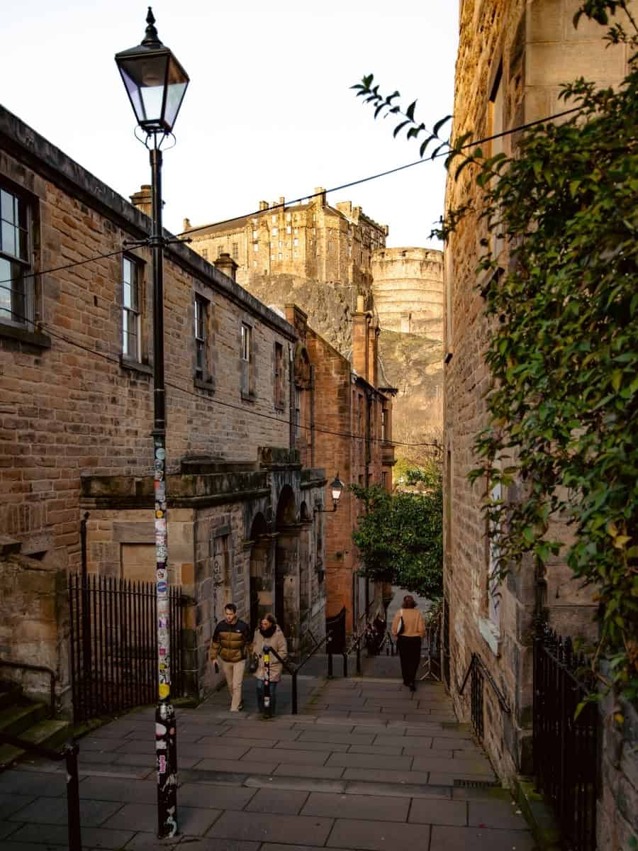 View of Edinburgh Castle from the Vennel viewpoint, framed by stone steps and surrounding buildings.