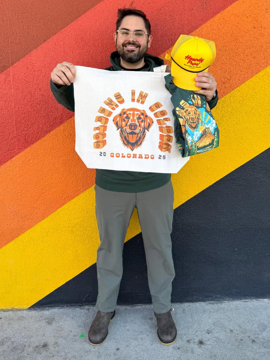 Joey holding a Goldens in Golden giveaway bundle with official YoColorado merchandise.
