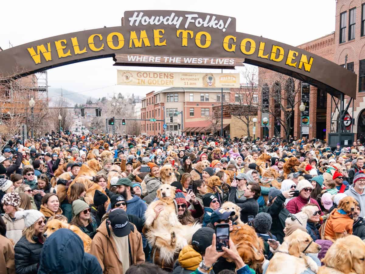 Group of people standing under the Welcome to Golden sign during the Goldens in Golden 2024 event in downtown Golden, Colorado.
