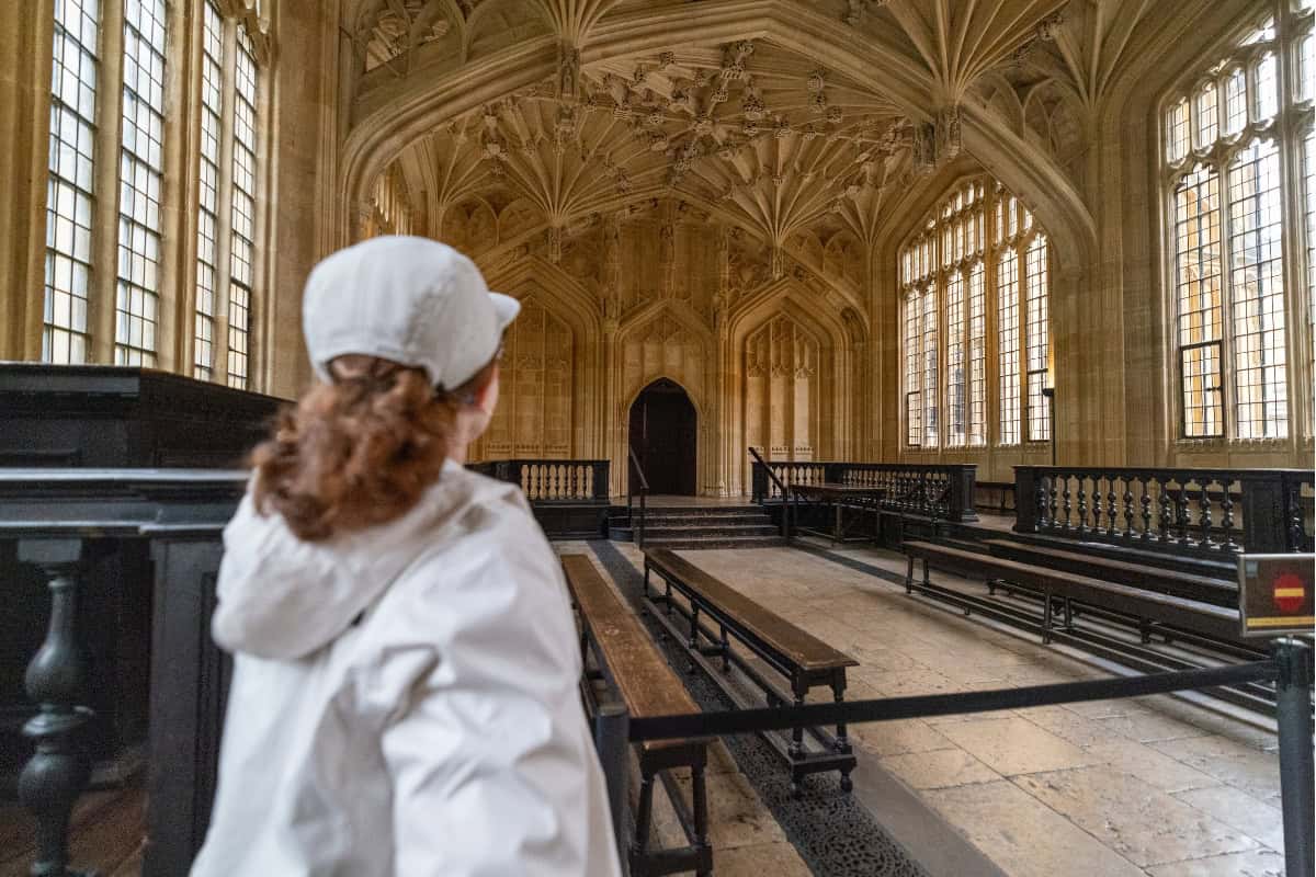 Katie standing inside the Divinity School Oxford gothic vaulted ceiling