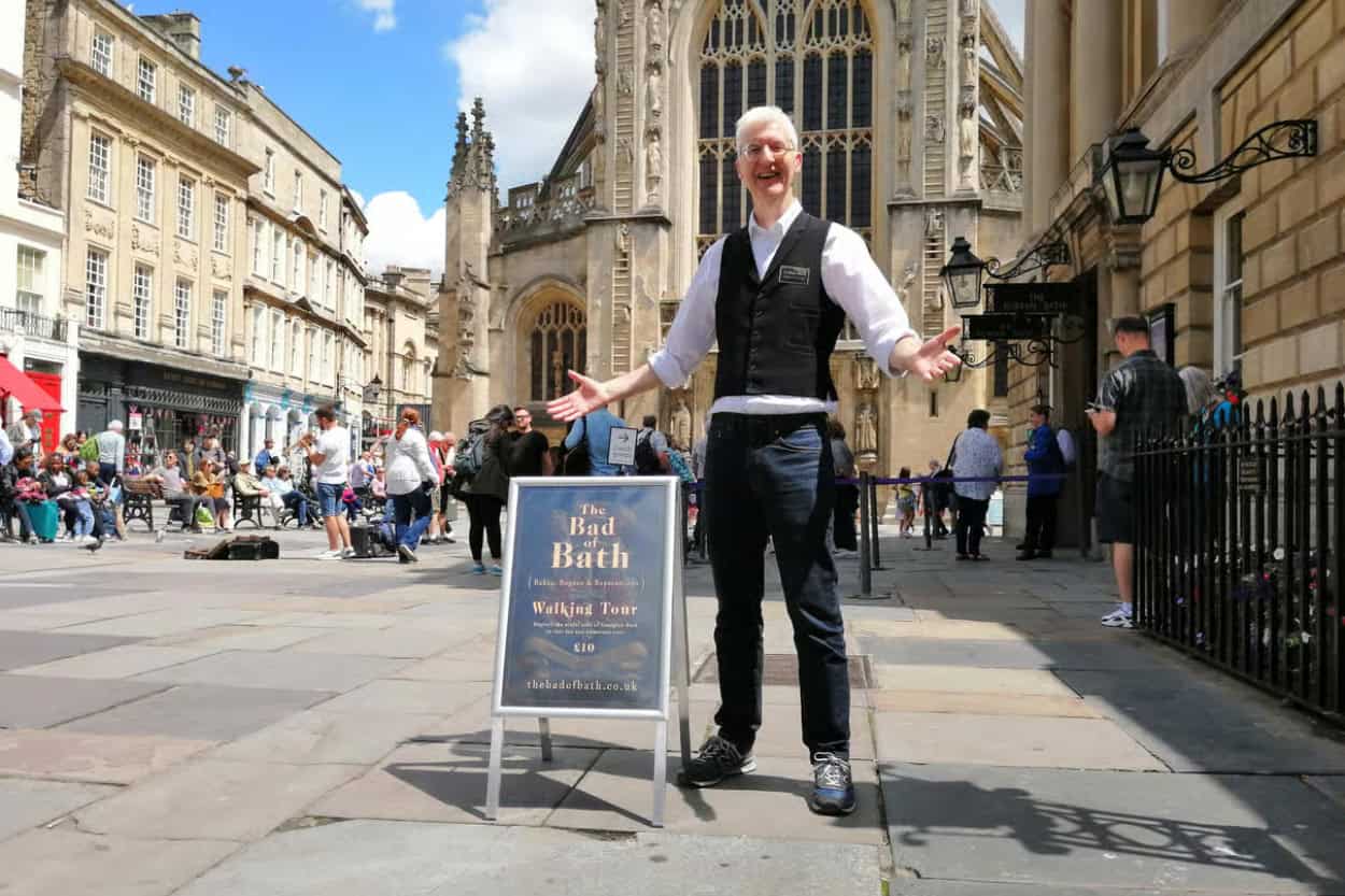 Tour guide standing in front of The Bad of Bath walking tour sign in Bath, England