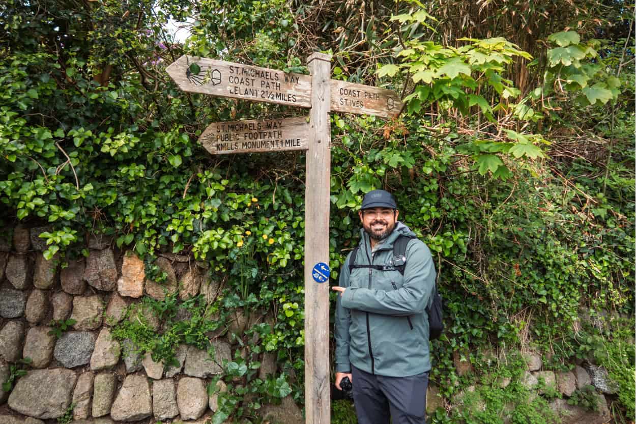 Joey standing in front of the Camino Inglés to Santiago sign in St. Ives, England. Macs Adventure Review.