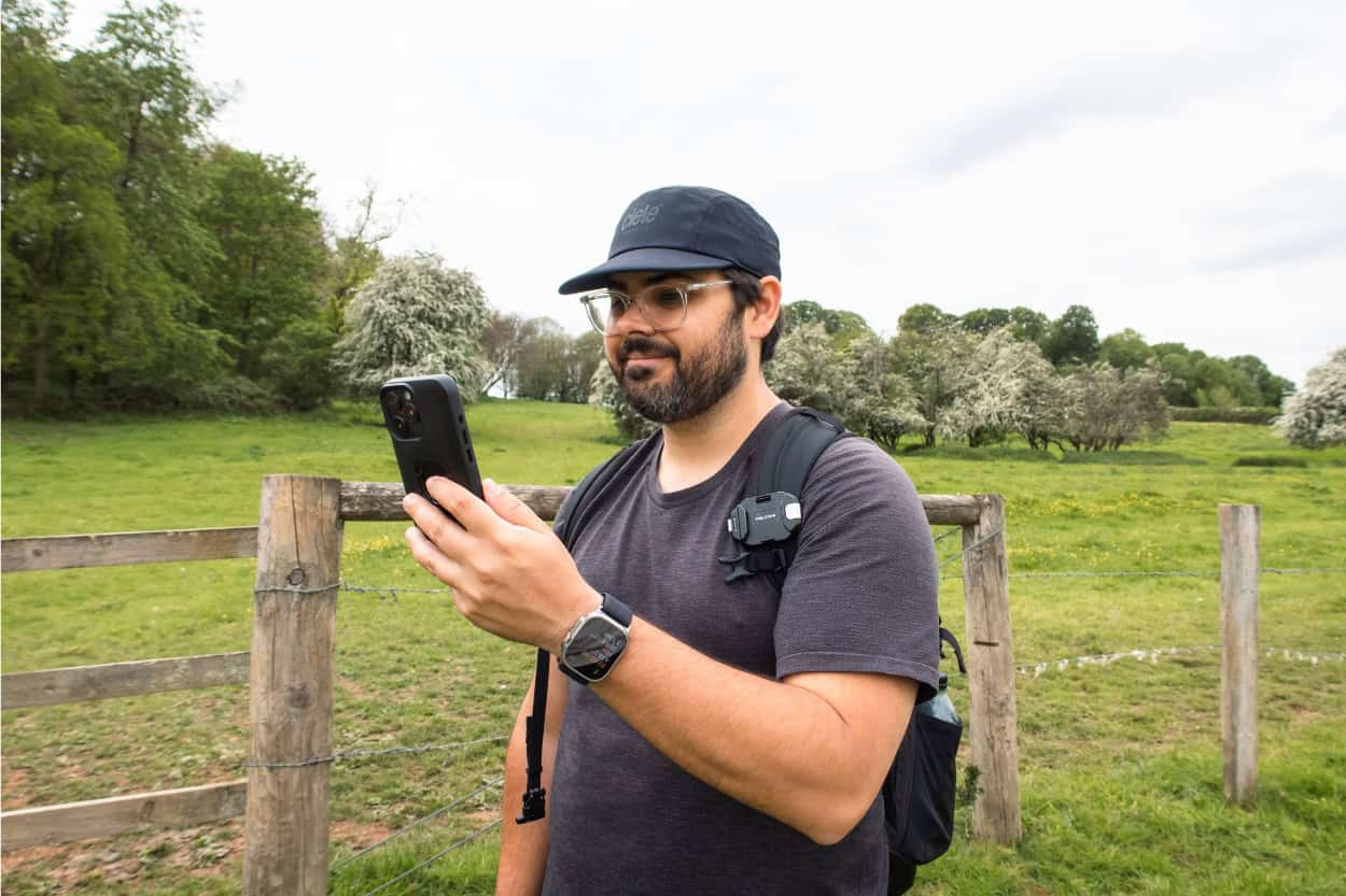 Joey holding his phone up pretending to take a call while walking in the English countryside