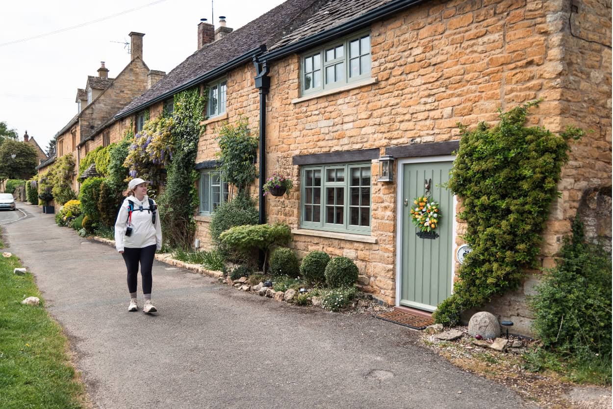Woman in rain jacket and trail running shoes walking the Cotswolds England