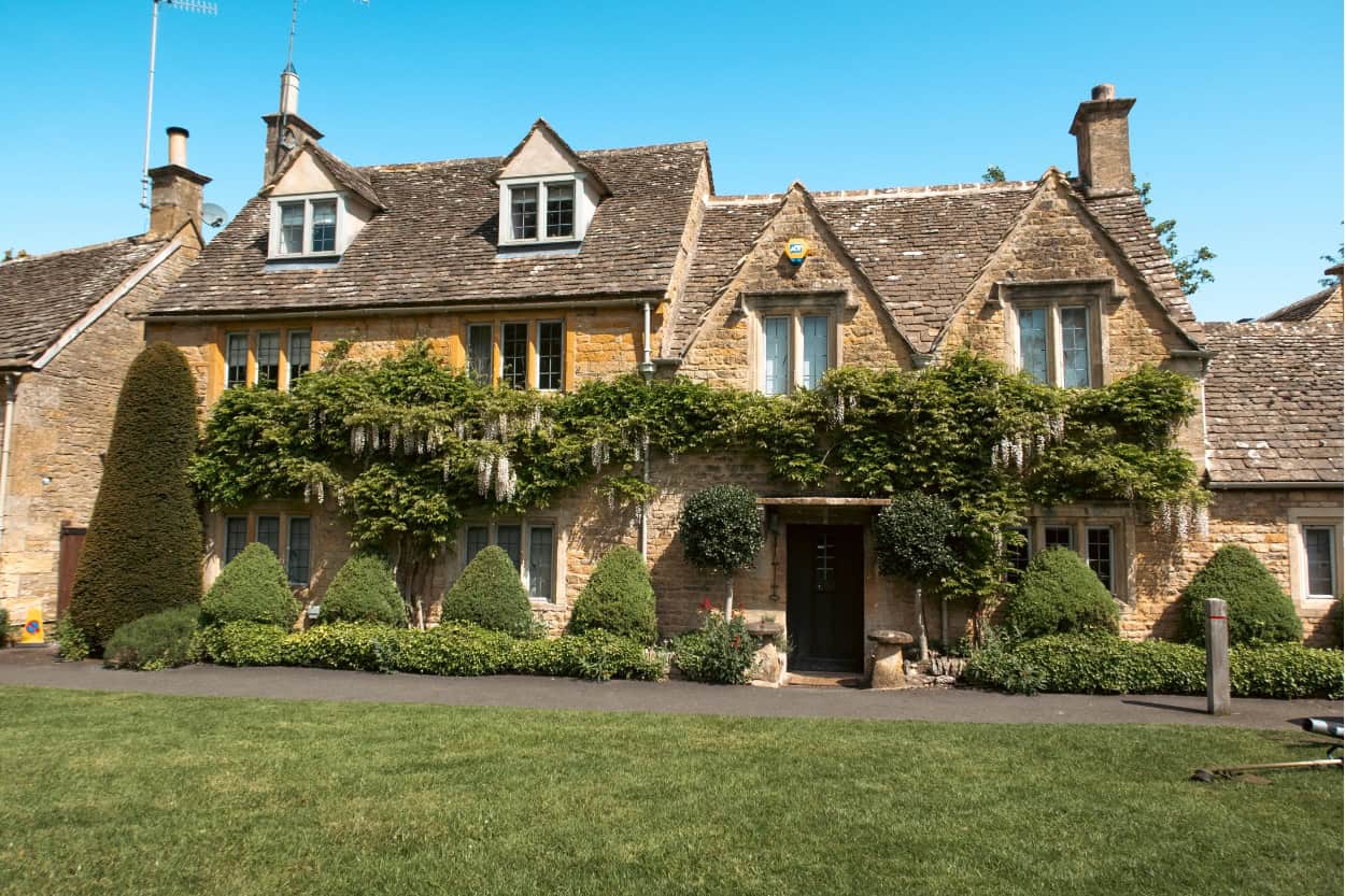 Golden stone cottage covered in vines walking the Cotswolds in Lower Slaughter