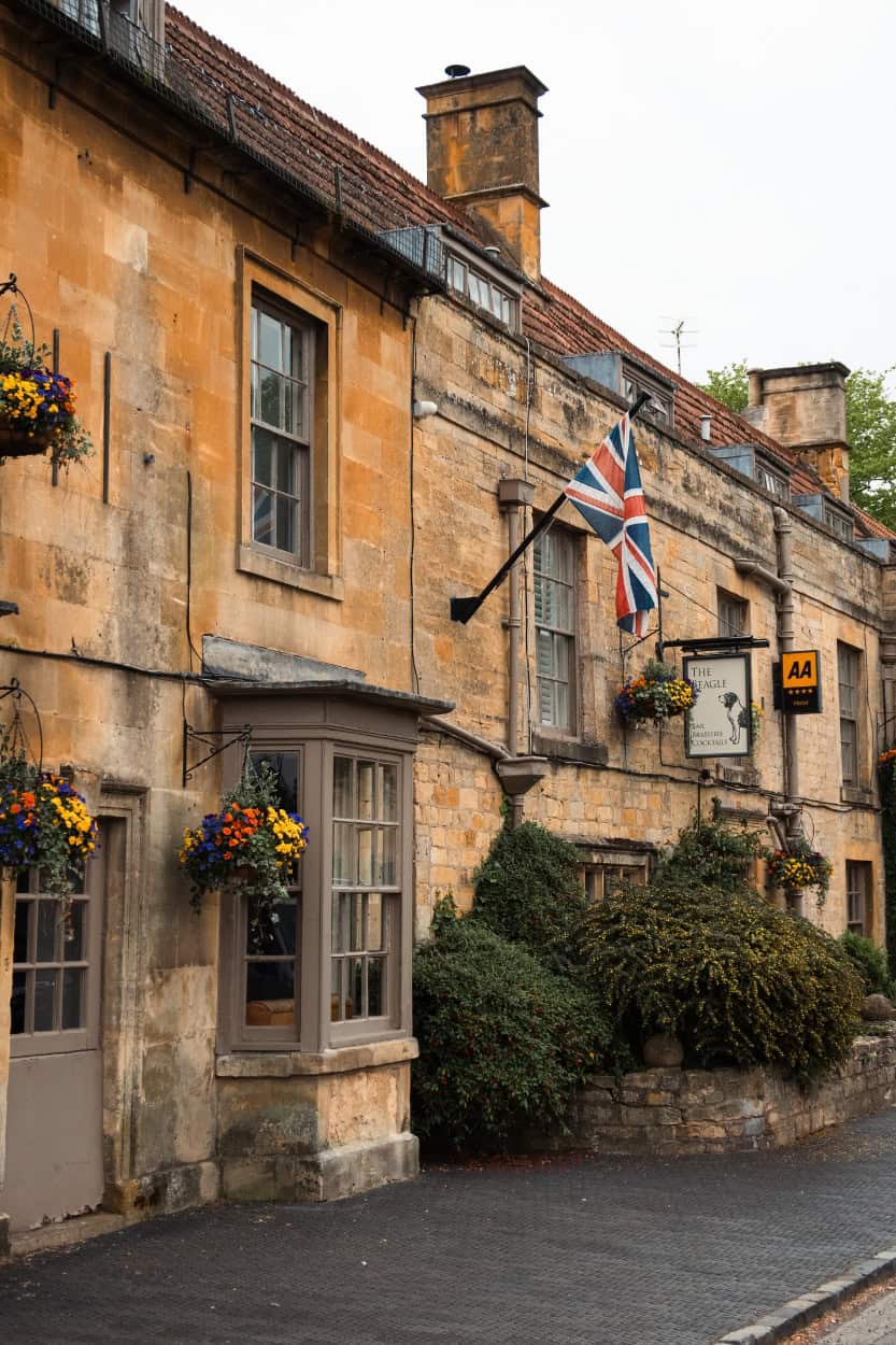 Golden stone buildings with Union Jack flag walking the Cotswolds England