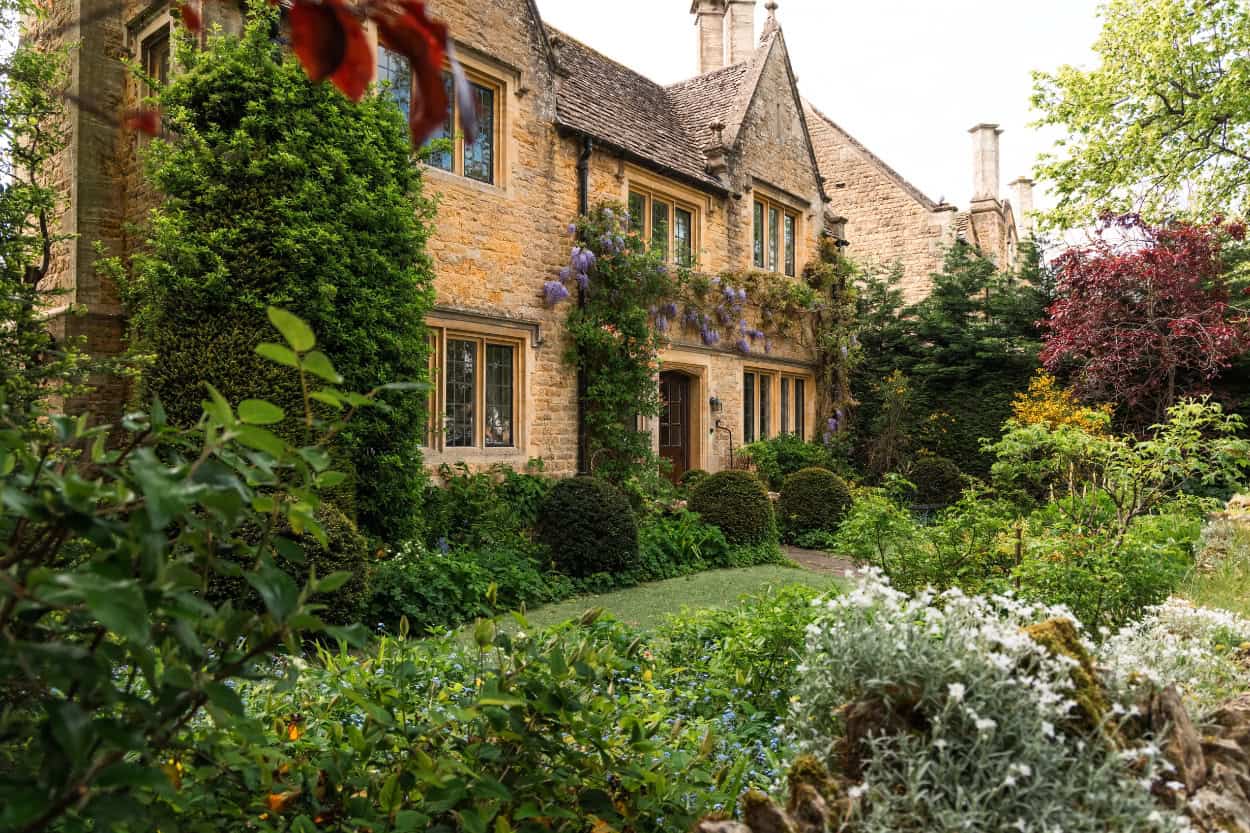 Golden stone cottage with climbing plants in Bourton-on-the-Water walking the Cotswolds England