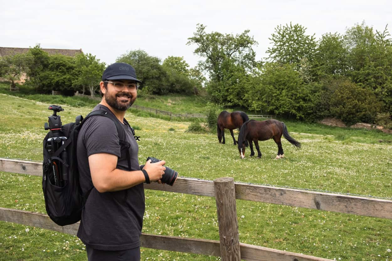 Man with camera standing near horses walking the Cotswolds near Moreton-in-Marsh