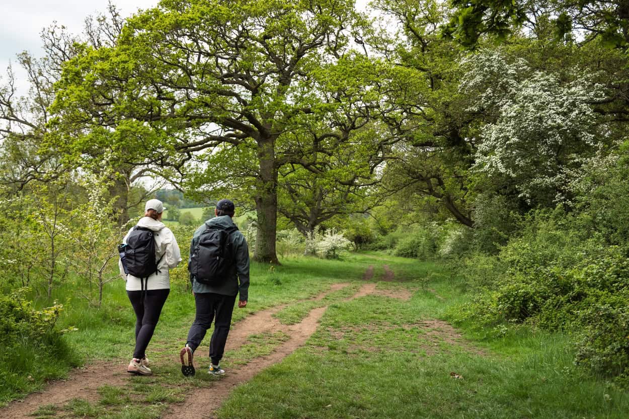 Couple walking a double track path through farmland in the Cotswolds countryside England