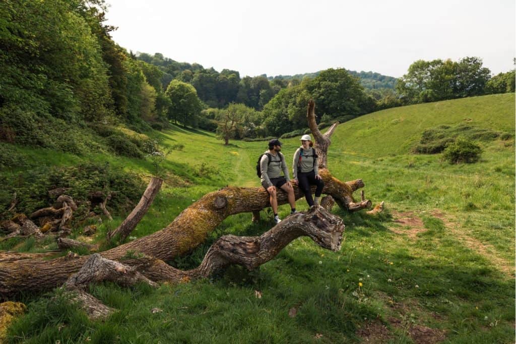 Katie and Joe sitting on a fallen tree along the Bath Skyline Trail in England