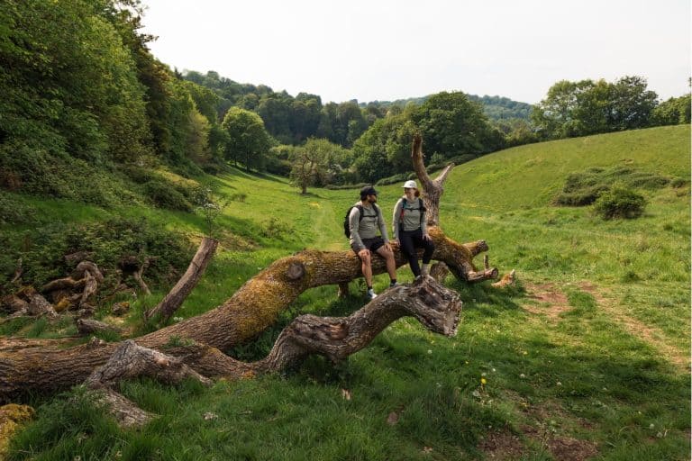 Katie and Joe sitting on a fallen tree along the Bath Skyline Trail in England