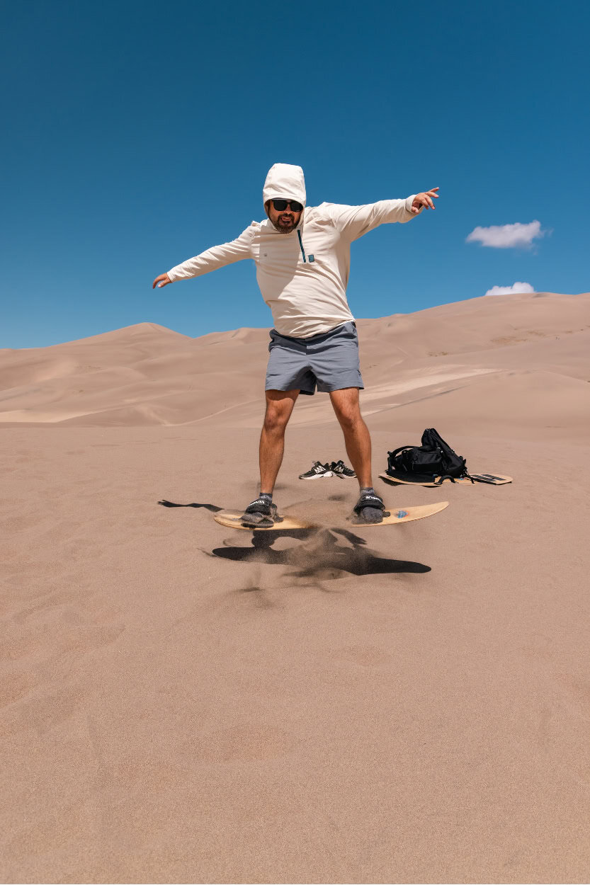 Man jumping a trick on a sand board at Great Sand Dunes National Park in Colorado