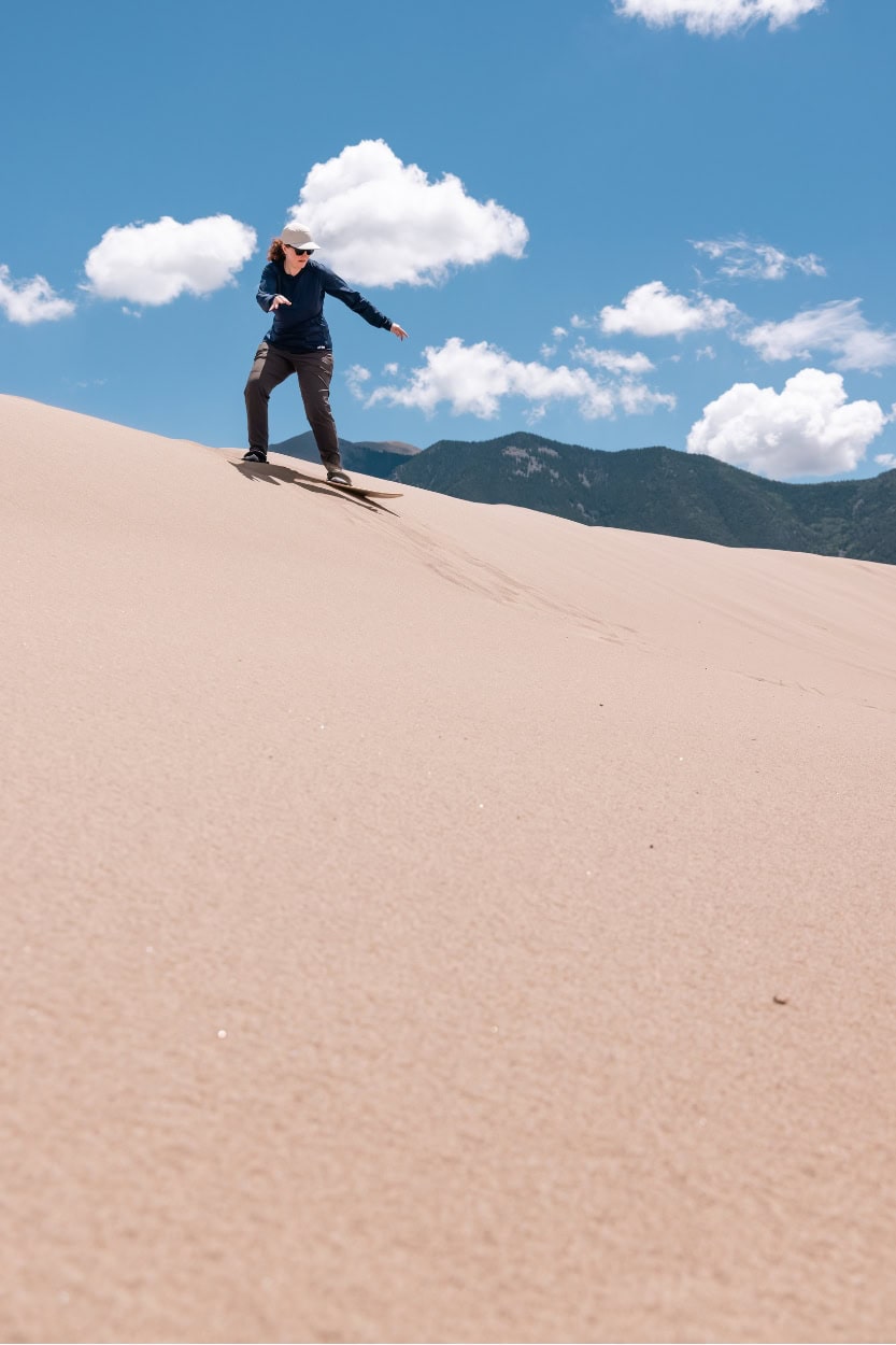 Woman sandboarding down a dune at Great Sand Dunes National Park in Colorado