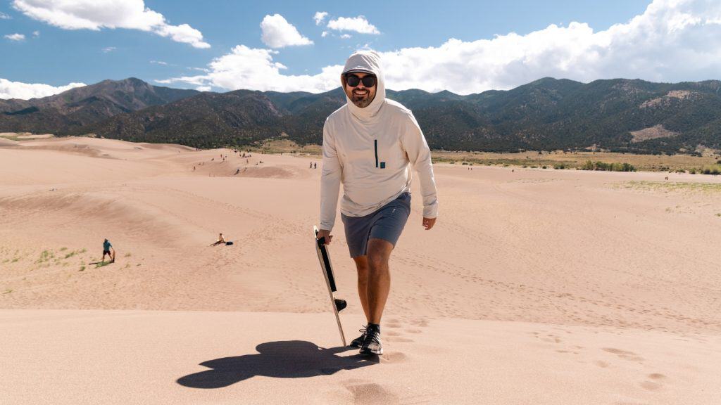 Man carrying a sandboard up a sand dune at Great Sand Dunes National Park, Colorado
