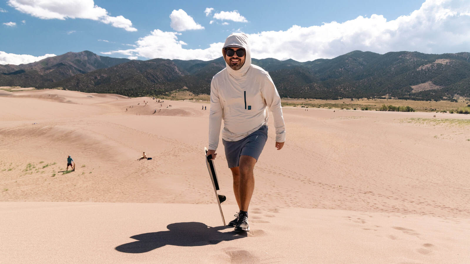 Man carrying a sandboard up a sand dune at Great Sand Dunes National Park, Colorado